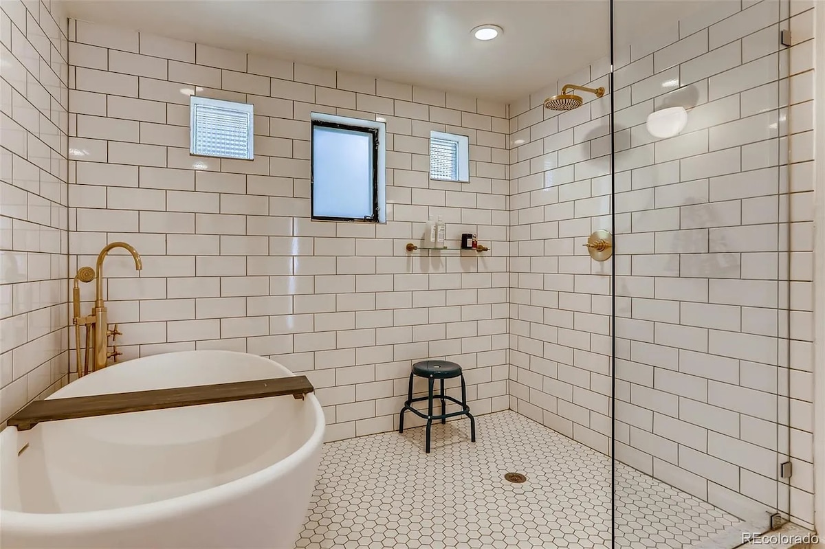 Remodeled white tiled bathroom with freestanding soaking tub and separate shower